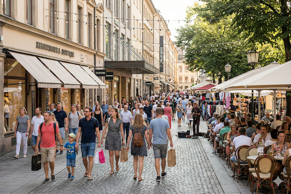Busy pedestrian shopping street with retail storefronts and cafes