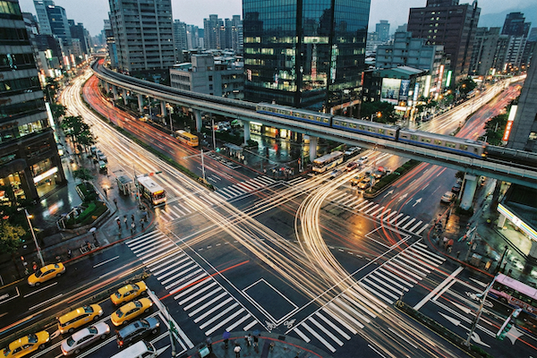Aerial night view of a busy urban intersection with transit, buses, and traffic flows